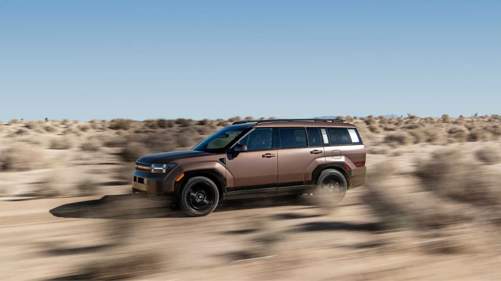 Dynamic side profile photo of a bronze 2025 Hyundai Santa Fe Hybrid Off-Road in the desert.