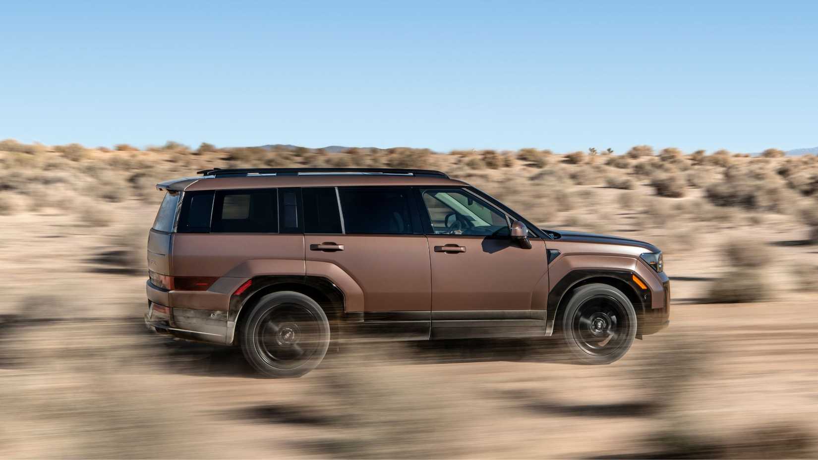 Dynamic side profile shot of a bronze 2025 Hyundai Santa Fe Hybrid off-roading in the desert.