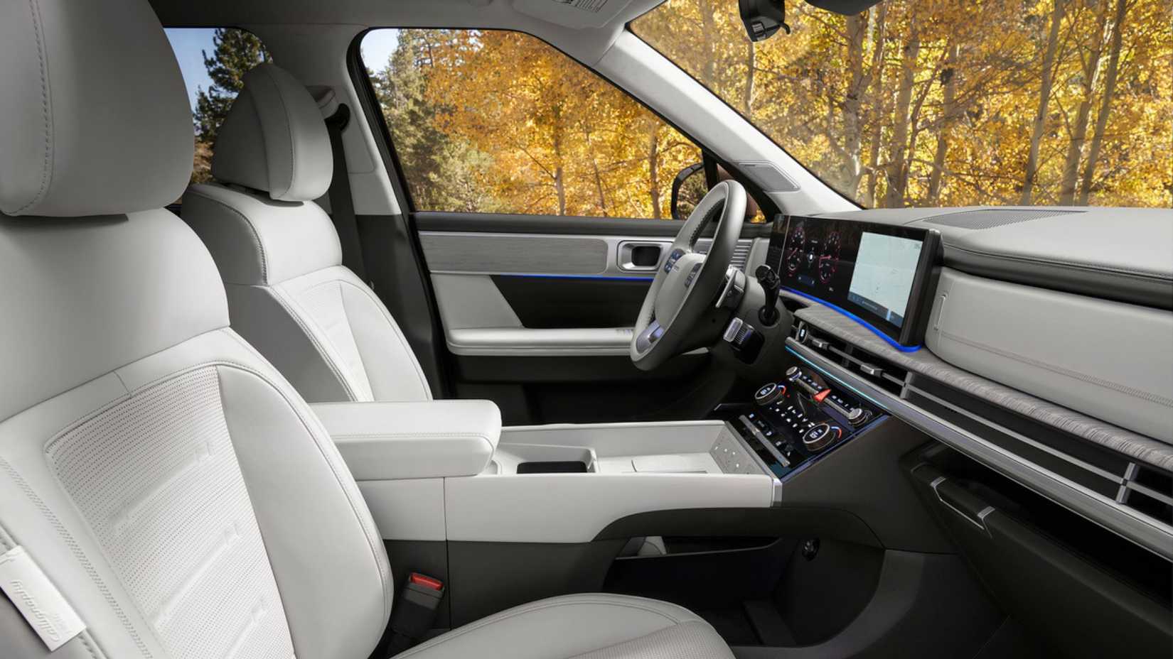 Close-up shot inside the cabin of a 2025 Hyundai Santa Fe Hybrid, showing the front seats covered in white leather.