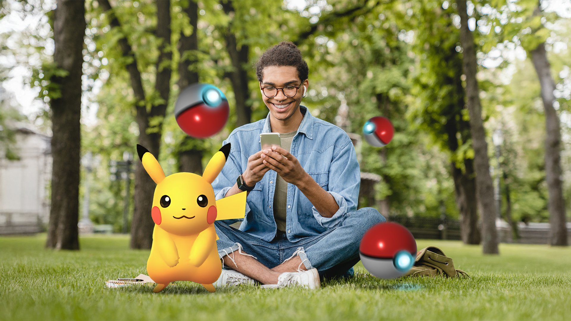 Young man sitting on the grass using his phone, surrounded by floating Poké Balls, with a Pikachu beside him.