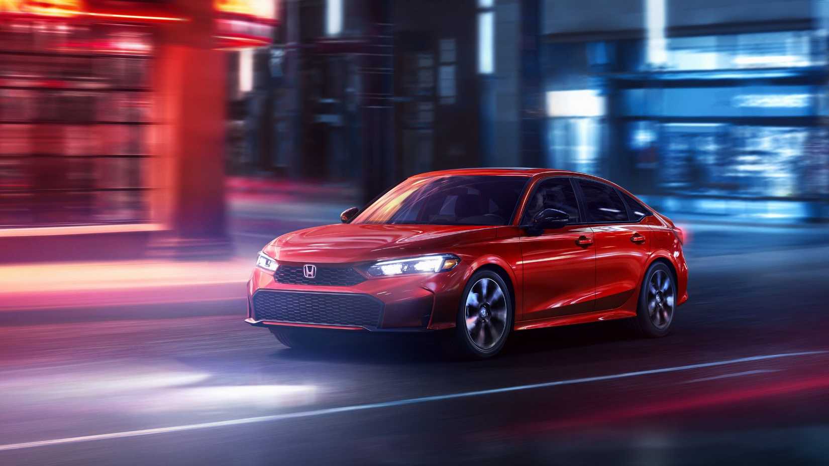 Dynamic front 3/4 shot of a red 2025 Honda Civic Sedan Sport Touring Hybrid driivng in a city.