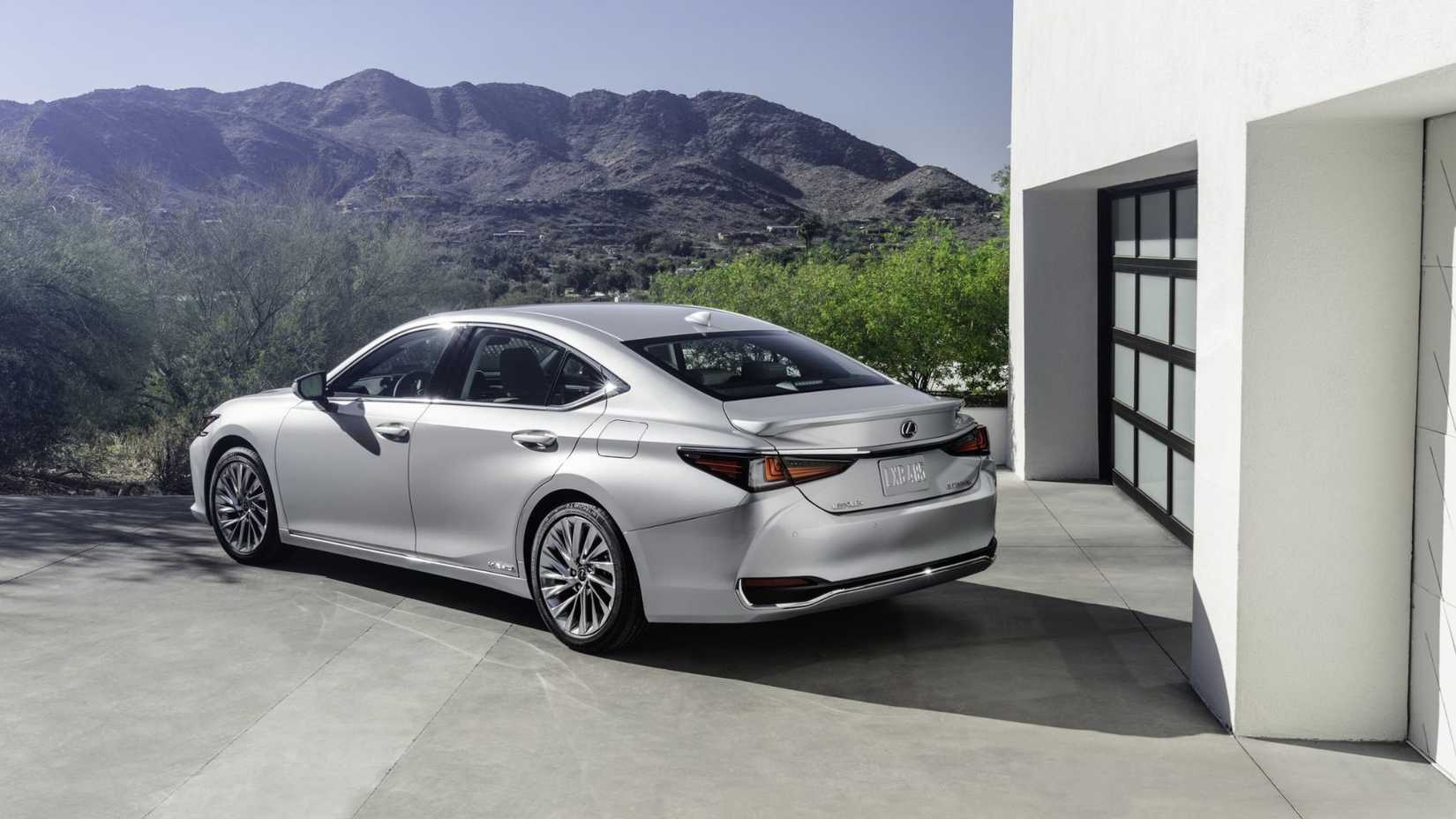Static rear 3/4 shot of silver 2022 Lexus ES 300h parked outside of a villa with hills in the background.