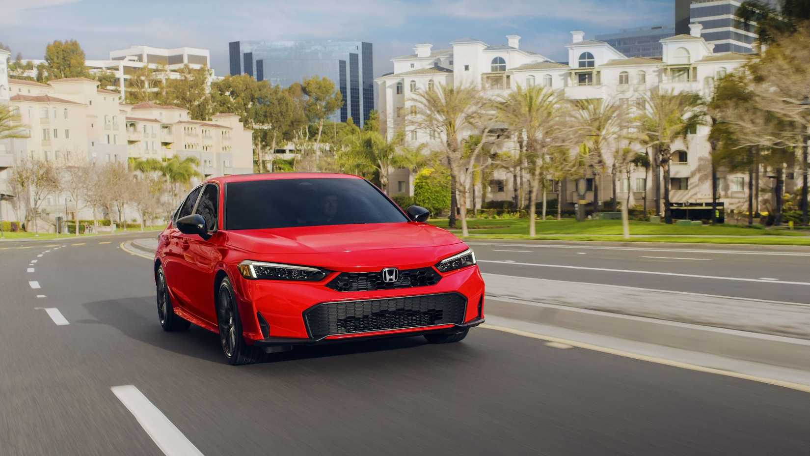 Dynamic front 3/4 shot of a red 2026 Honda Civic Sedan Sport Hybrid driving in a city.