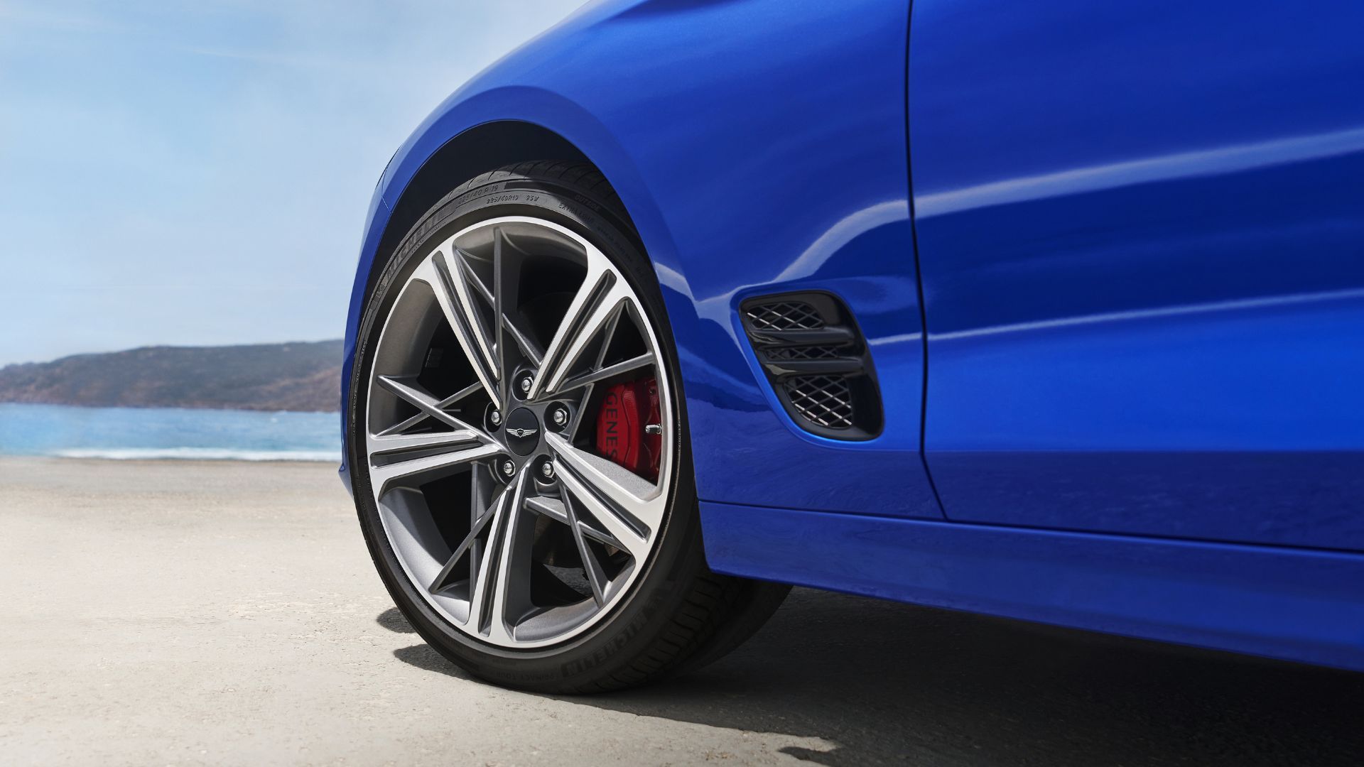 Close-up shot of the alloy wheel on a blue 2025 Genesis G70.