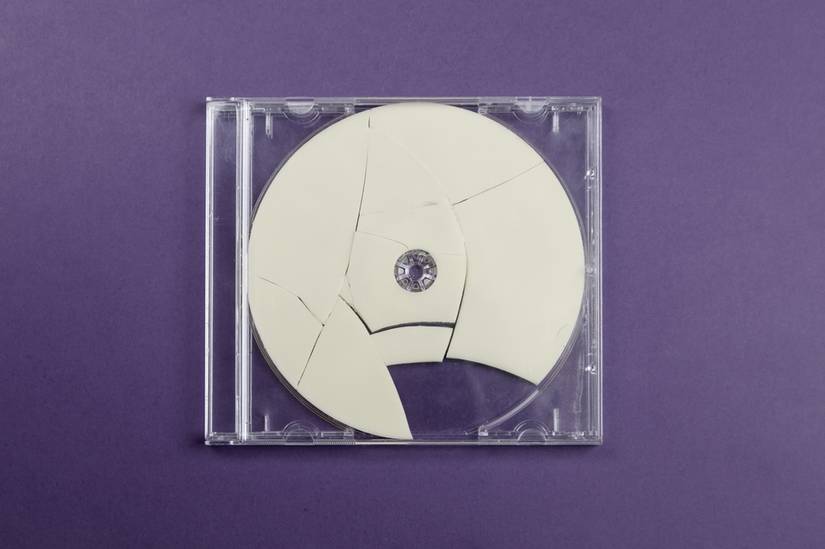 Disco roto en una caja sobre un fondo de color.