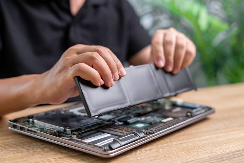 An open laptop with the battery pack removed by a technician.