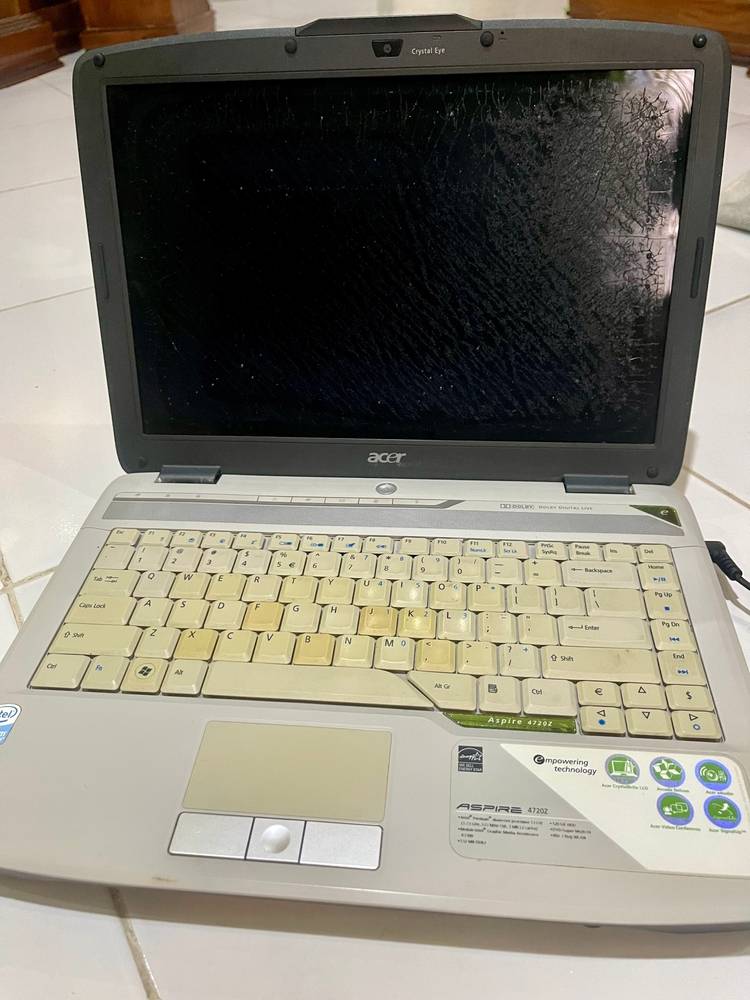 Um velho laptop Acer dos anos 2000 com uma tela rachada e um touchpad de estilo antigo.