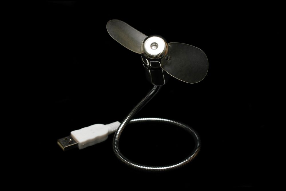 Um mini fã USB isolado no fundo preto.