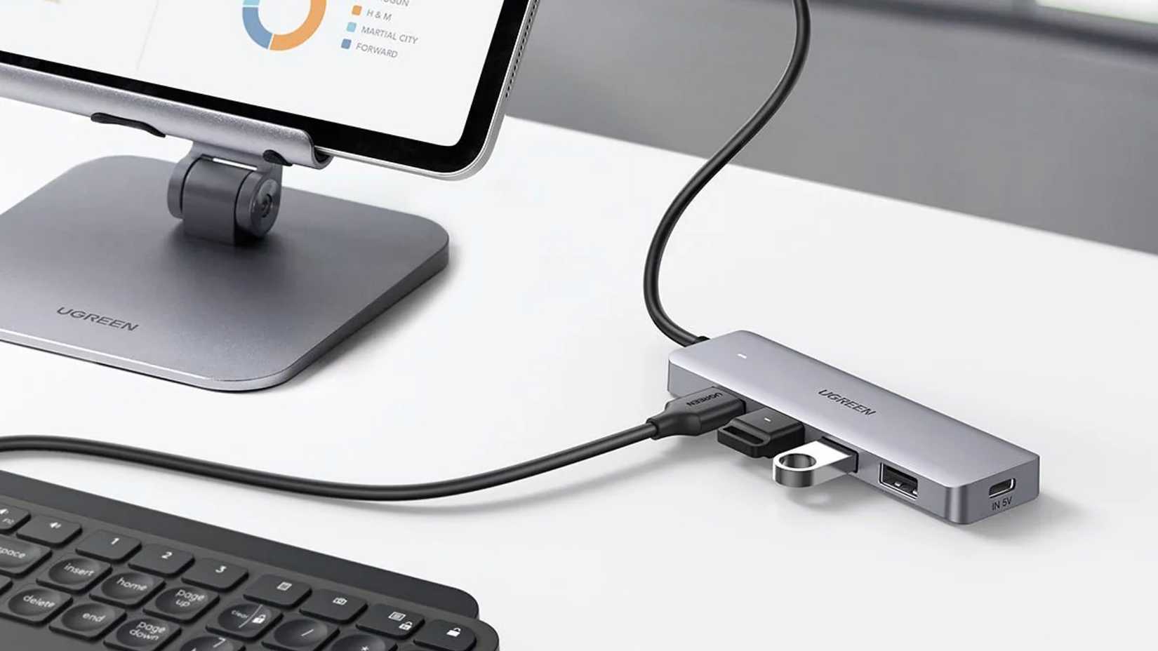 A Ugreen USB-C hub connected to a tablet and keyboard on a desk.