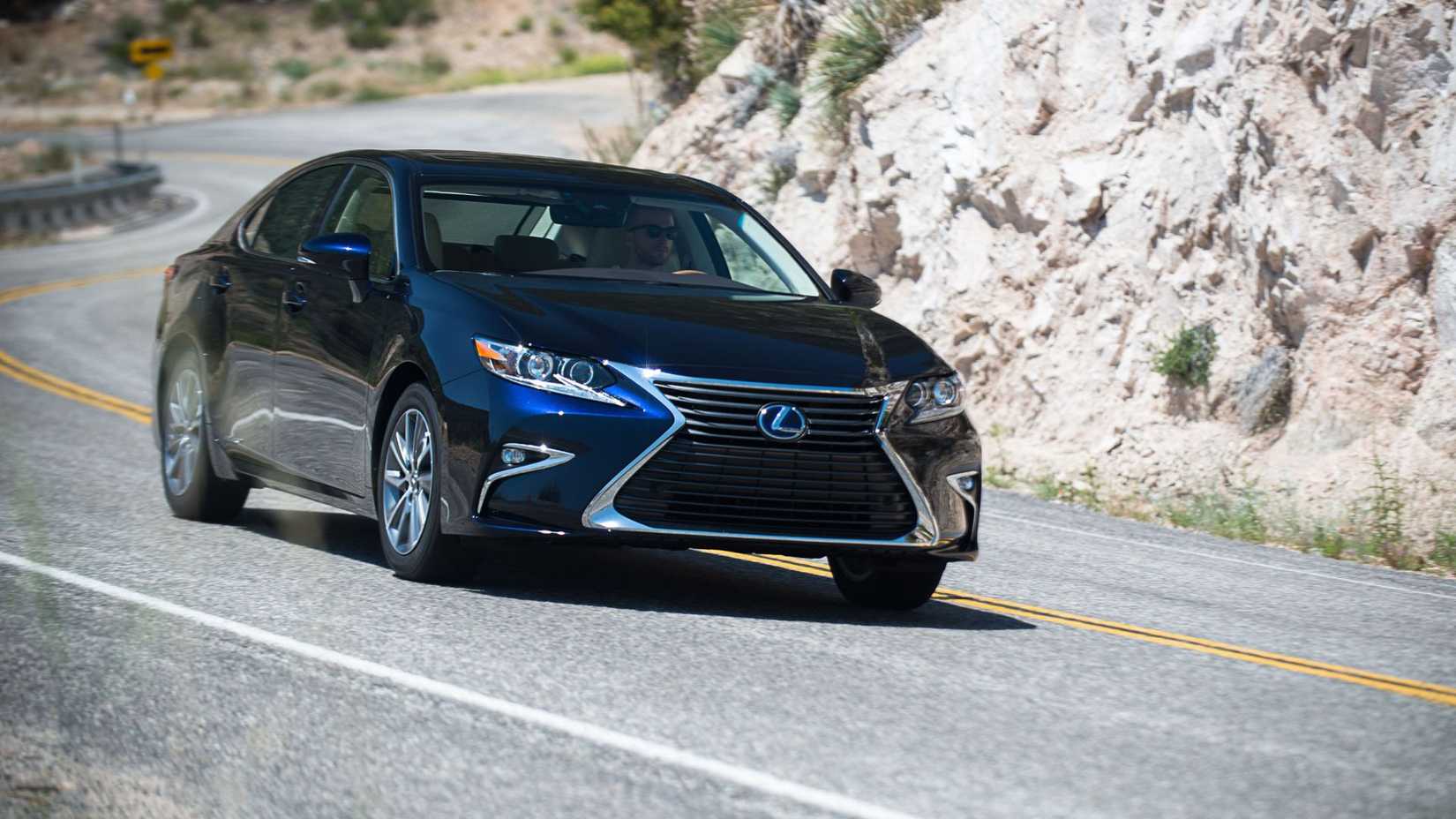 Dynamic front 3/4 shot of a navy 2018 Lexus ES 300h driving on a country road.