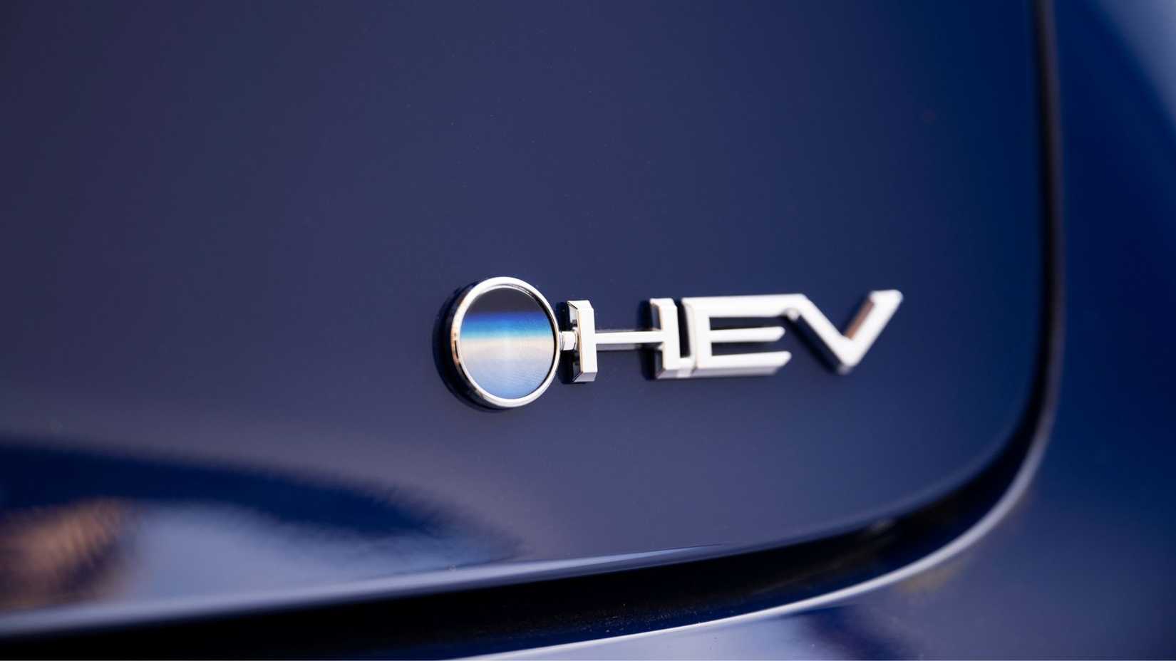 Close-up shot of the 'HEV' badging on a blue 2024 Toyota Prius Limited.