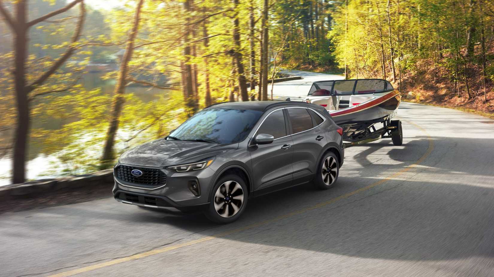 Dynamic front 3/4 shot of a gray 2025 Ford Escape Platinum towing a boat on a country road.