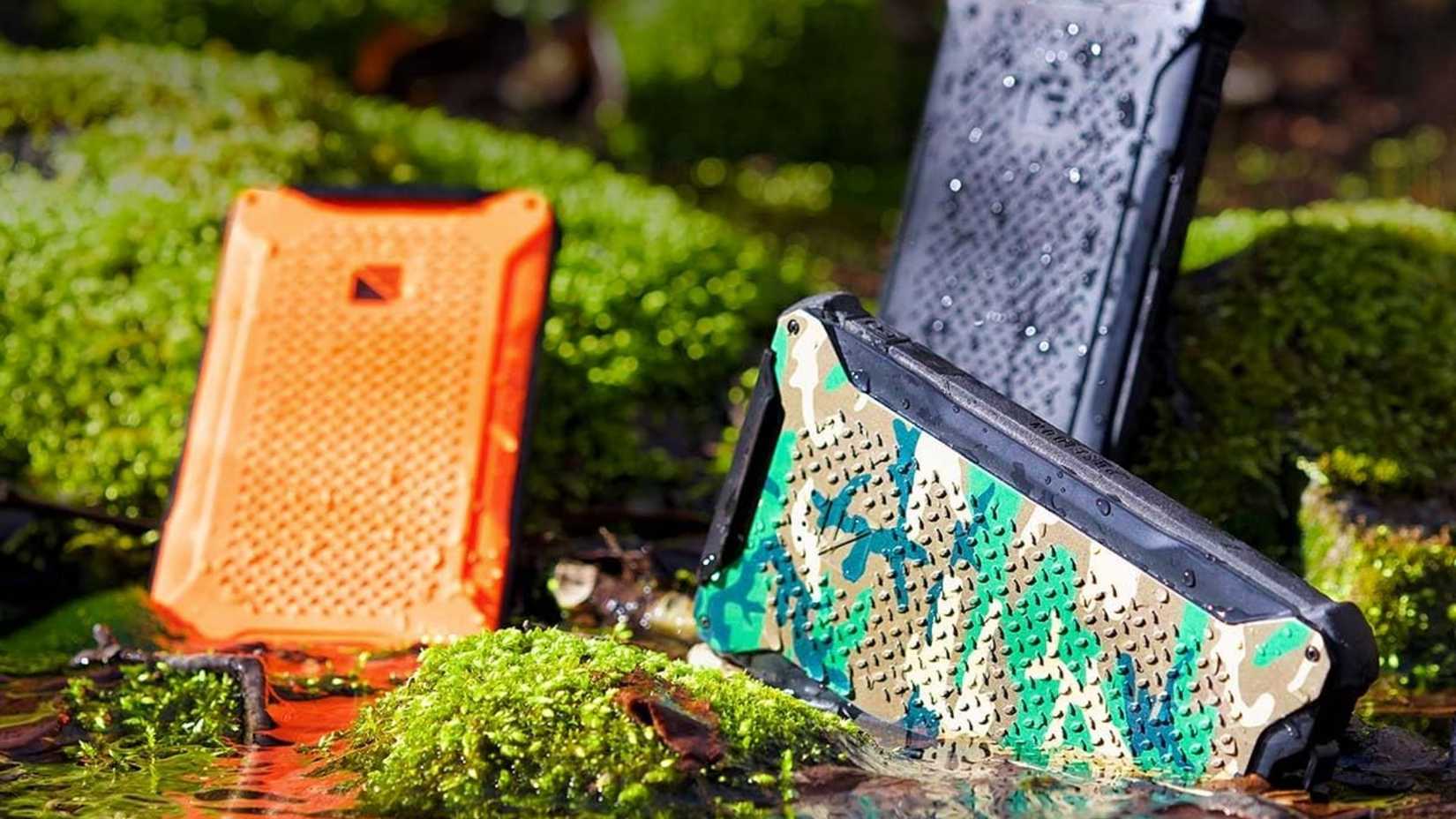 A few portable phone batteries in water near a grassy moss full area.