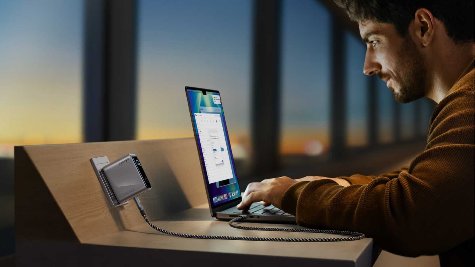 Persona que usa una computadora portátil conectada al cargador Anker Prime. 