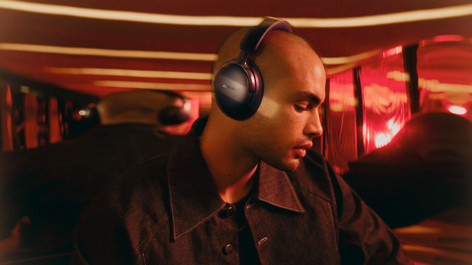 Bose 2nd gen QuietComfort Ultra Headphones being worn by a man in a red room