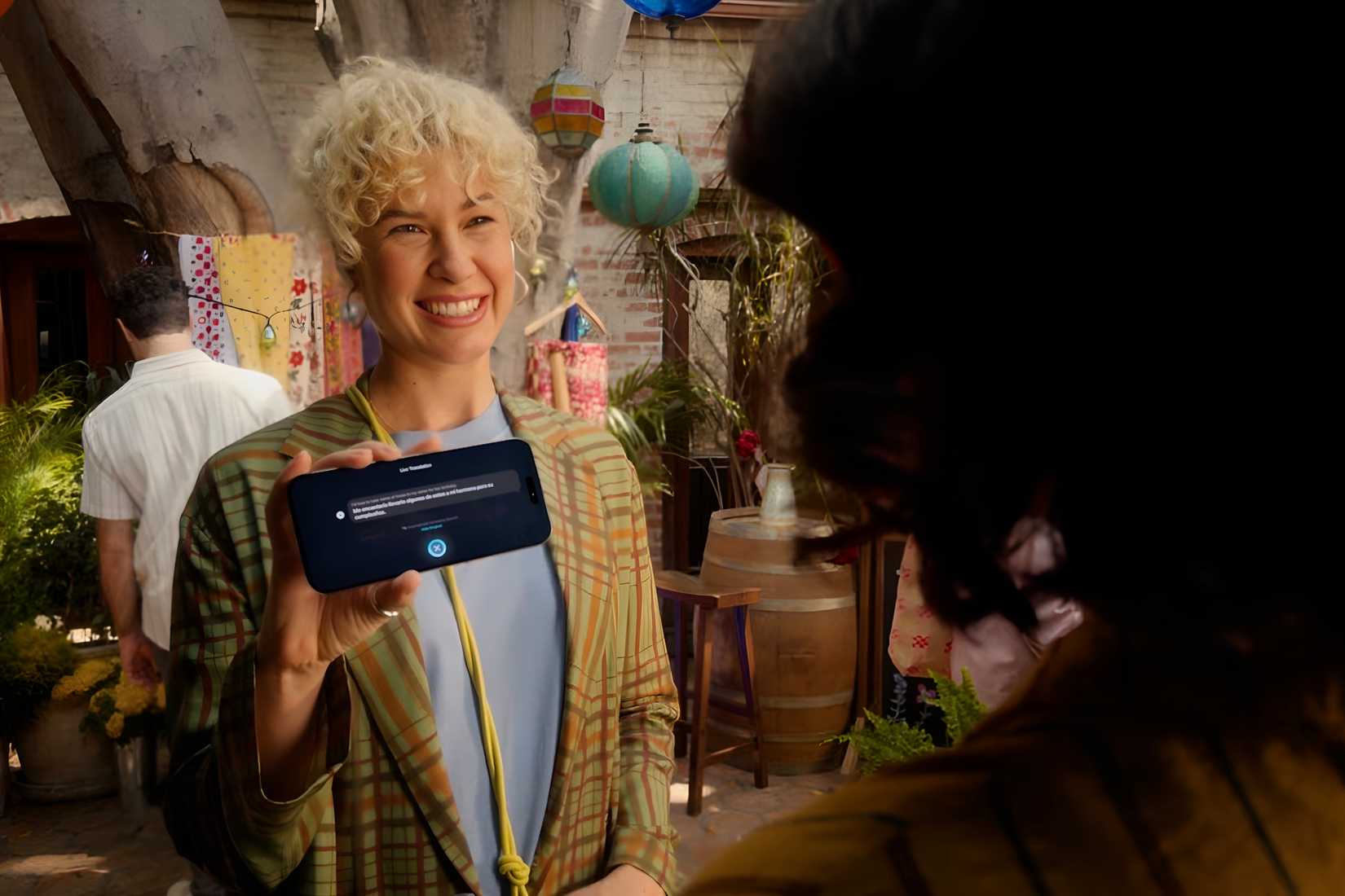 Live Translation happening through AirPods Pro and shown on Apple Intelligence-enabled iPhone.