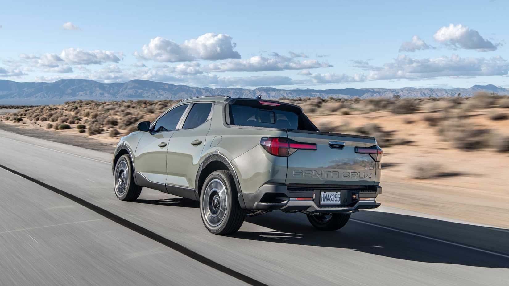 Dynamic rear 3/4 shot of a green 2025 Hyundai Santa Cruz Limited driving on a road through the desert.
