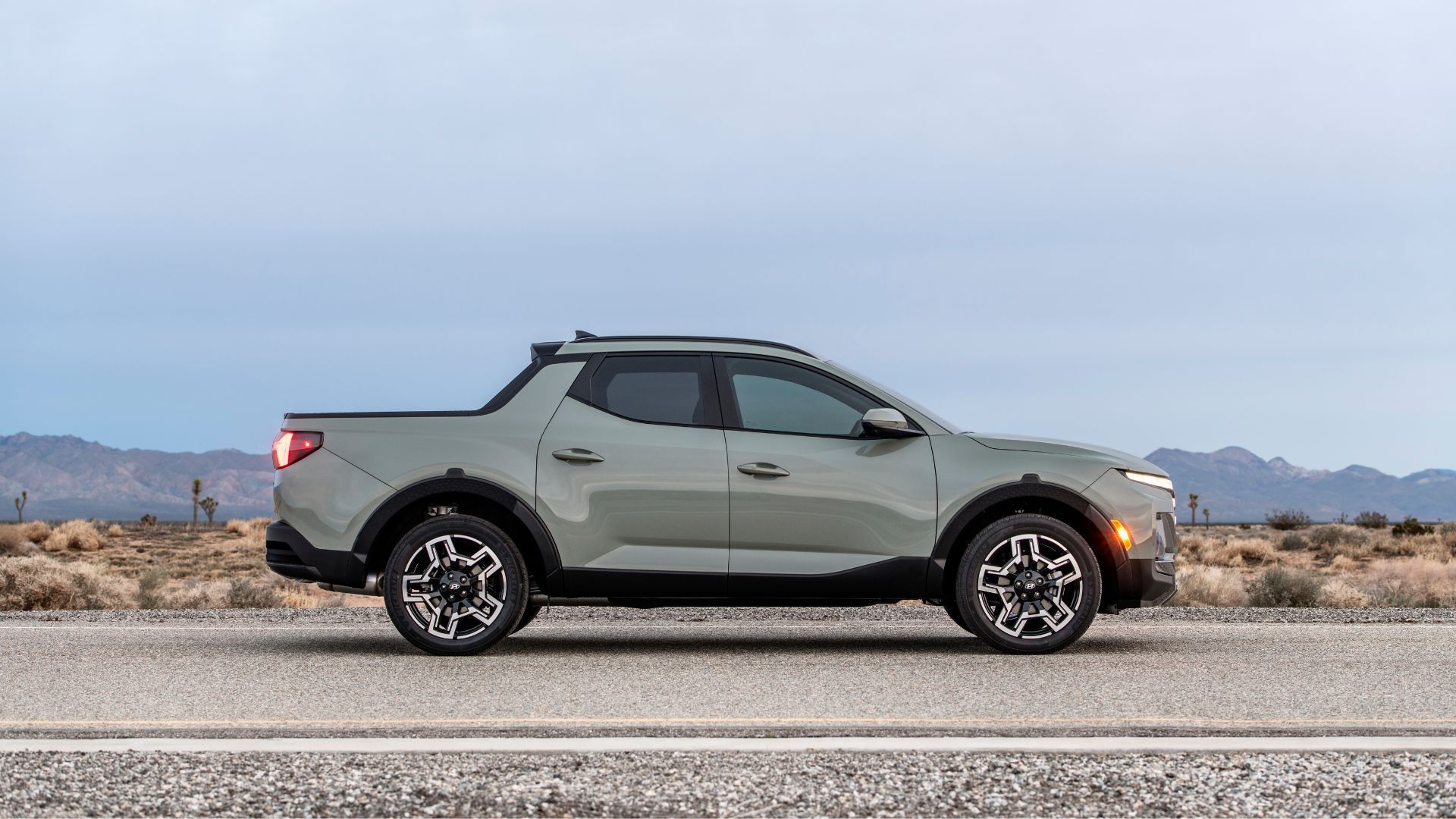Static side profile shot of a green 2025 Hyundai Sanata Cruz Limited parked on a road in the desert.