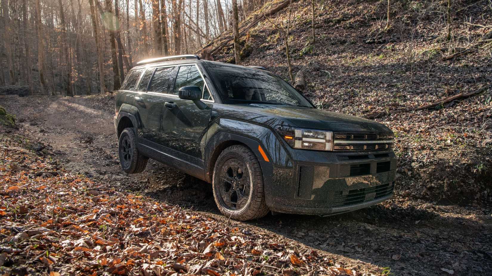 Dynamic front 3/4 shot of a 2026 Hyundai Santa Fe XRT off-roading in a forest.