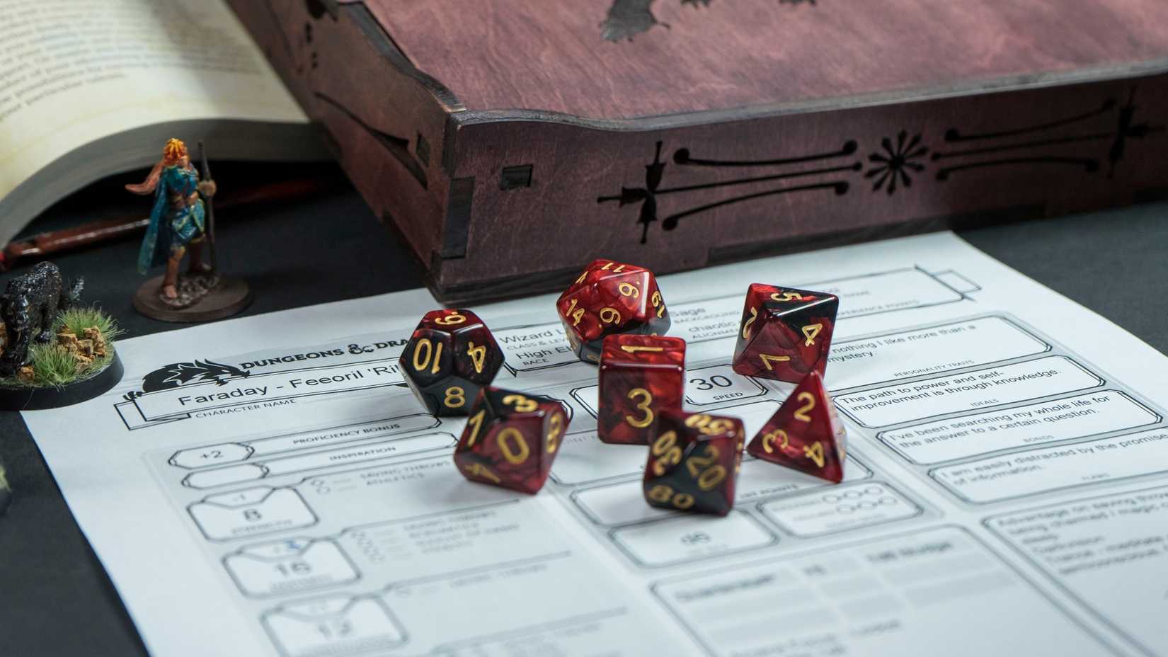 Set of red Dungeons & Dragons dice on a character sheet next to a figurine and book.