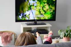 Young woman watching television with subtitles.