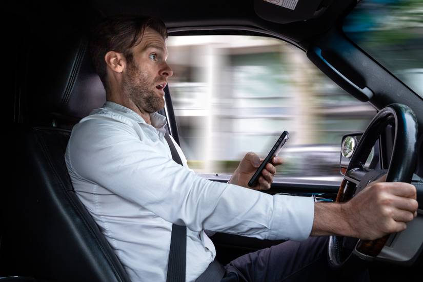 A man looks shocked while texting and driving.