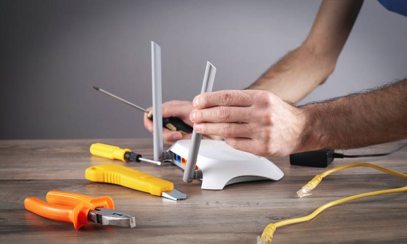 A person works on a router using tools.