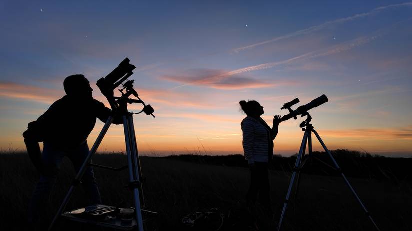 Amateur astronomers looking at the evening skies, observing planets, stars, Moon and other celestial objects with a telescope and camera on a star tracker.