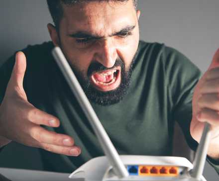 A man shouts angrily at a Wi-Fi router.