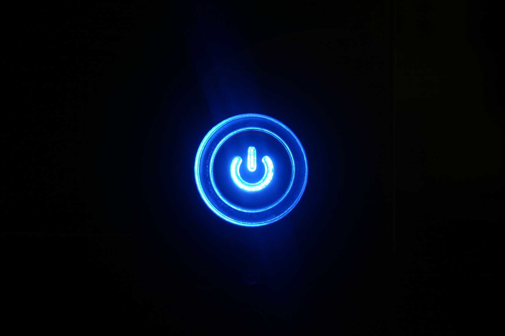 Blue glowing power button on black background.