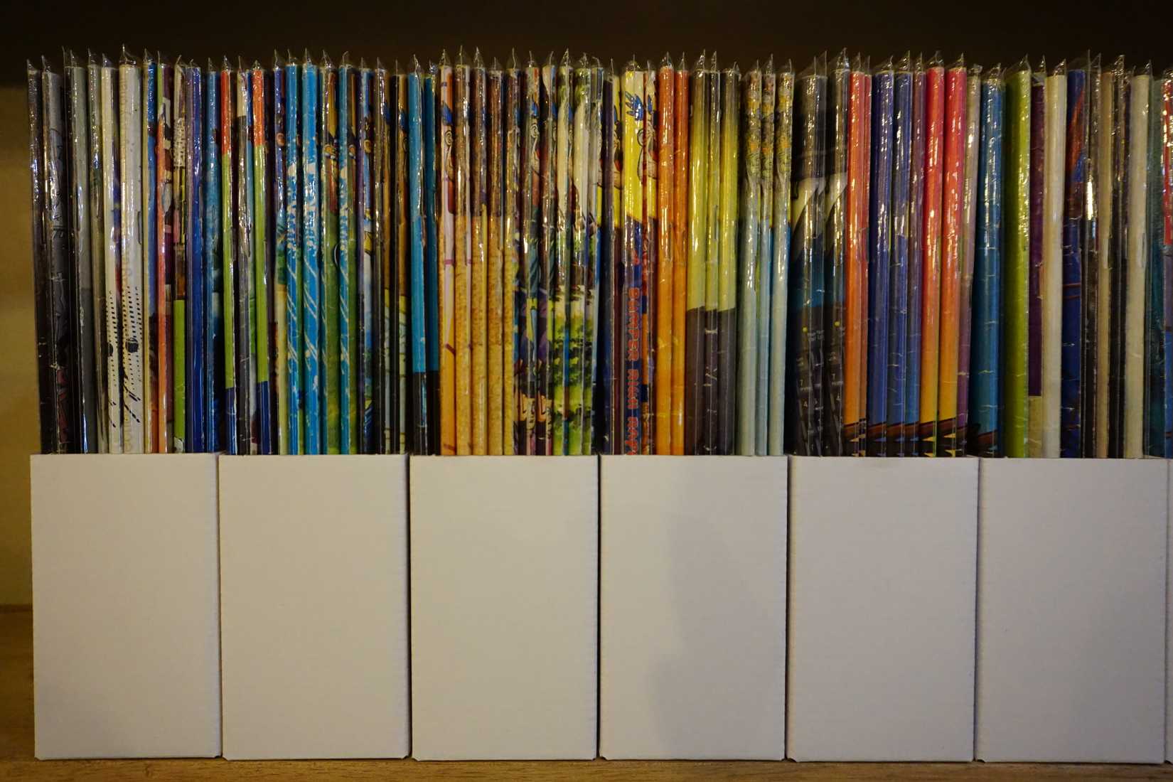 Comics sealed in plastic and stored upright in boxes.