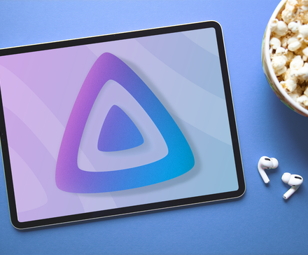 Планшет с лого Jellyfin на экране, рядом миска попкорна и беспроводные наушники.