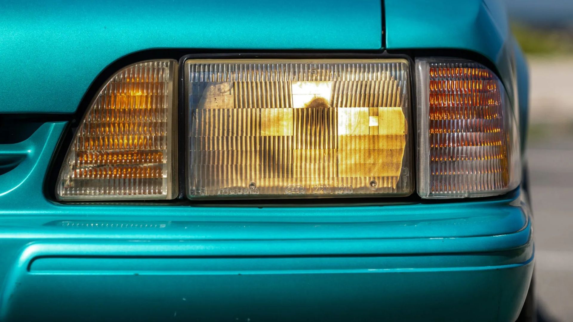 Gros plan du phare d'une Ford Mustang LX 5.0 bleue de 1993.