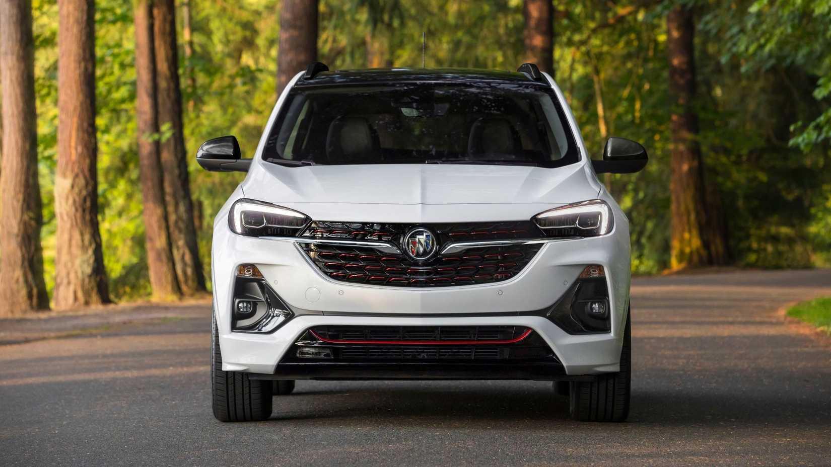 Static front-end shot of a white 2020 Buick Encore GX ST parked on a road lined with trees.