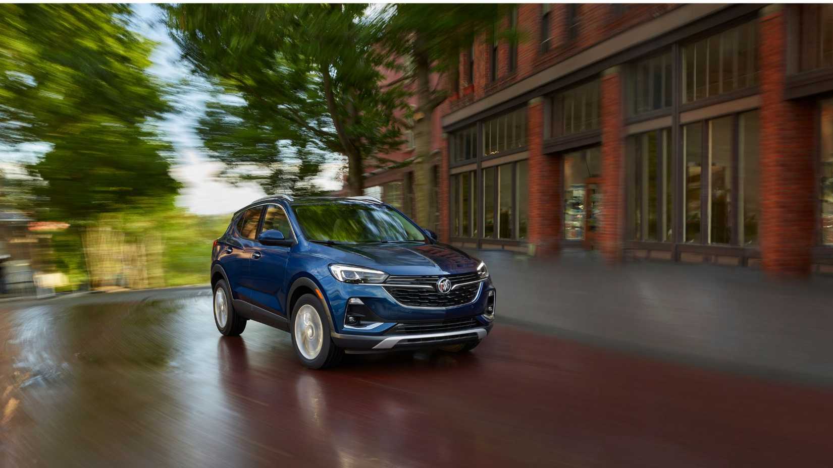 Dynamic front 3/4 shot of a blue 2021 Buick Encore GX driving in a city.