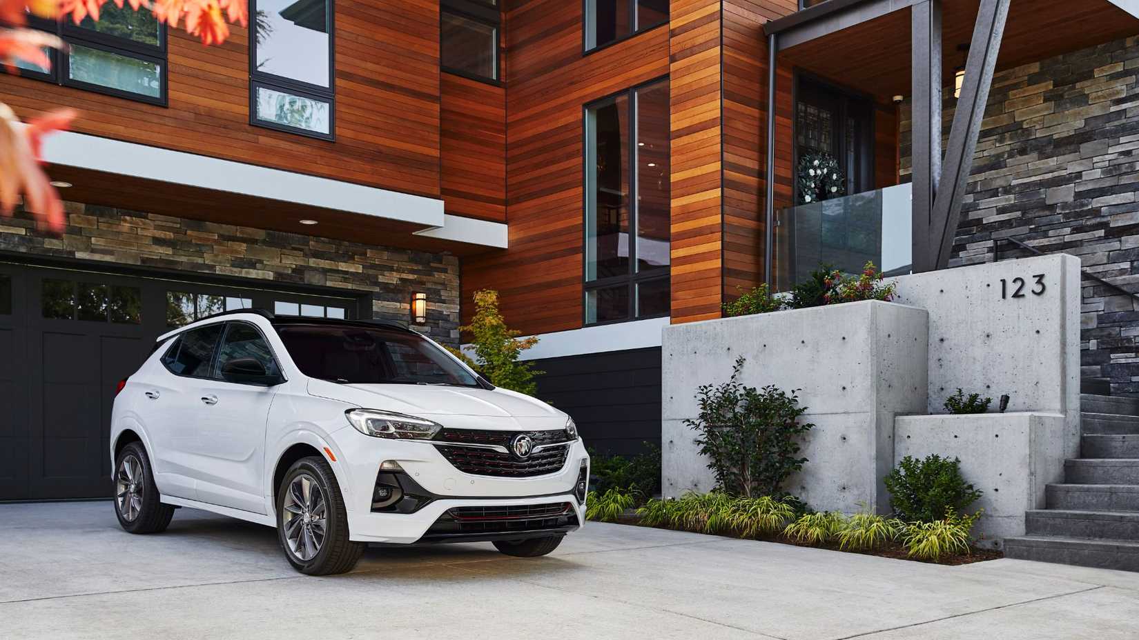 Static front 3/4 shot of a white 2022 Buick Encore GX parked on the driveway of a home.