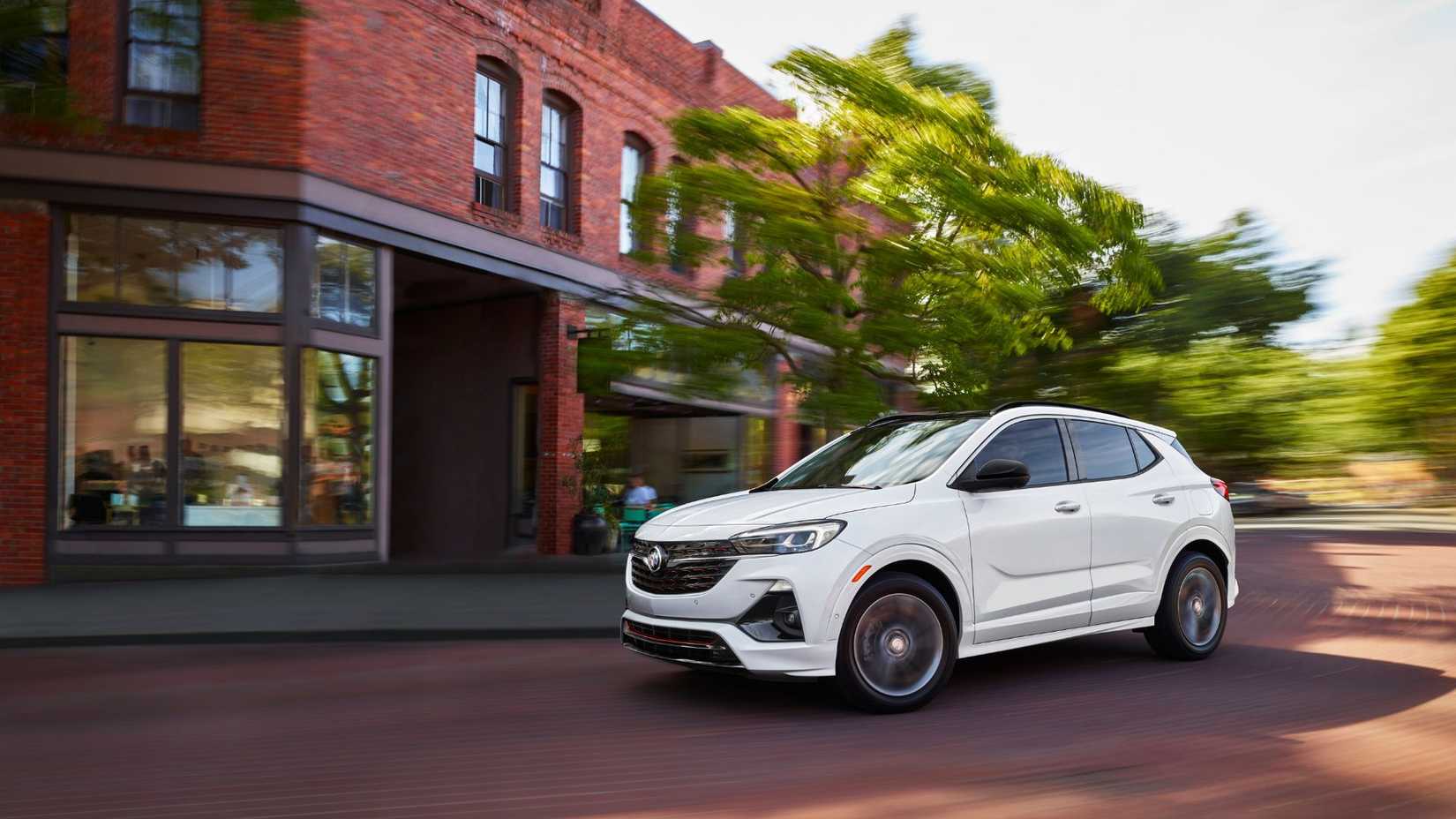 Dynamic front 3/4 shot of a shite 2022 Buick Encore GX driving in a city.