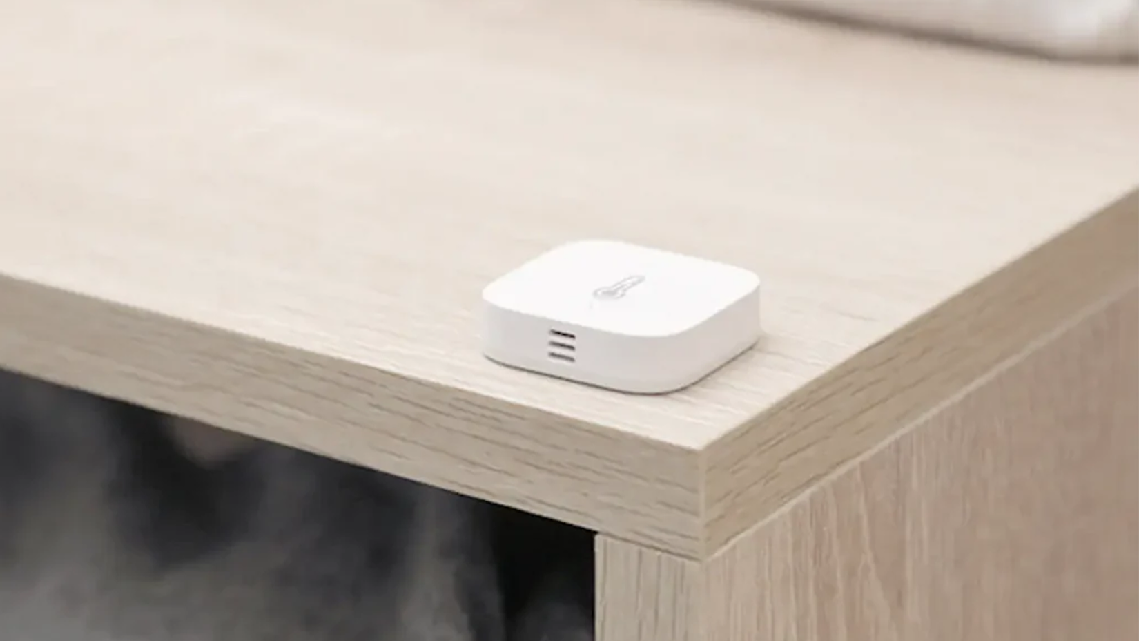 An Aqara Temperature and Humidity Sensor lying on a table.