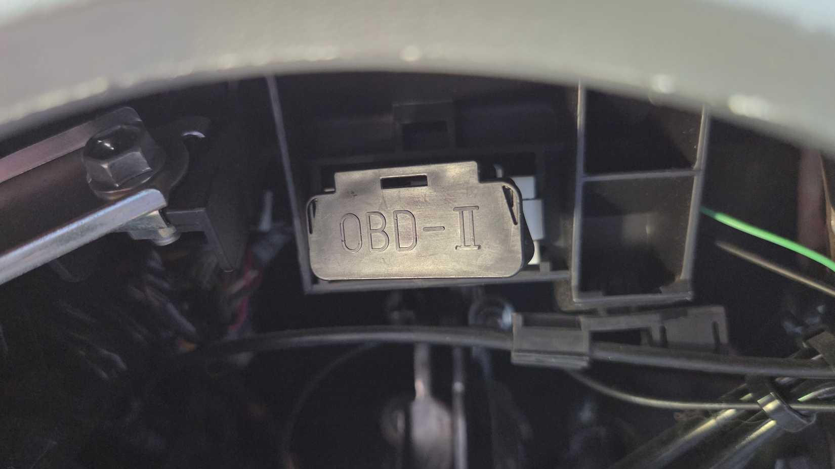 OBD-II port inside of a car with the cover on. 