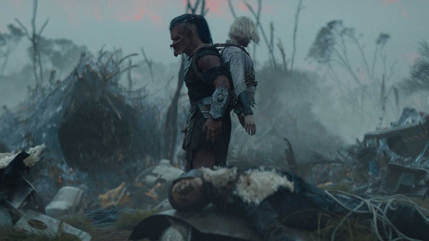 First look image of Dek carrying Thia on his back in Predator: Badlands.