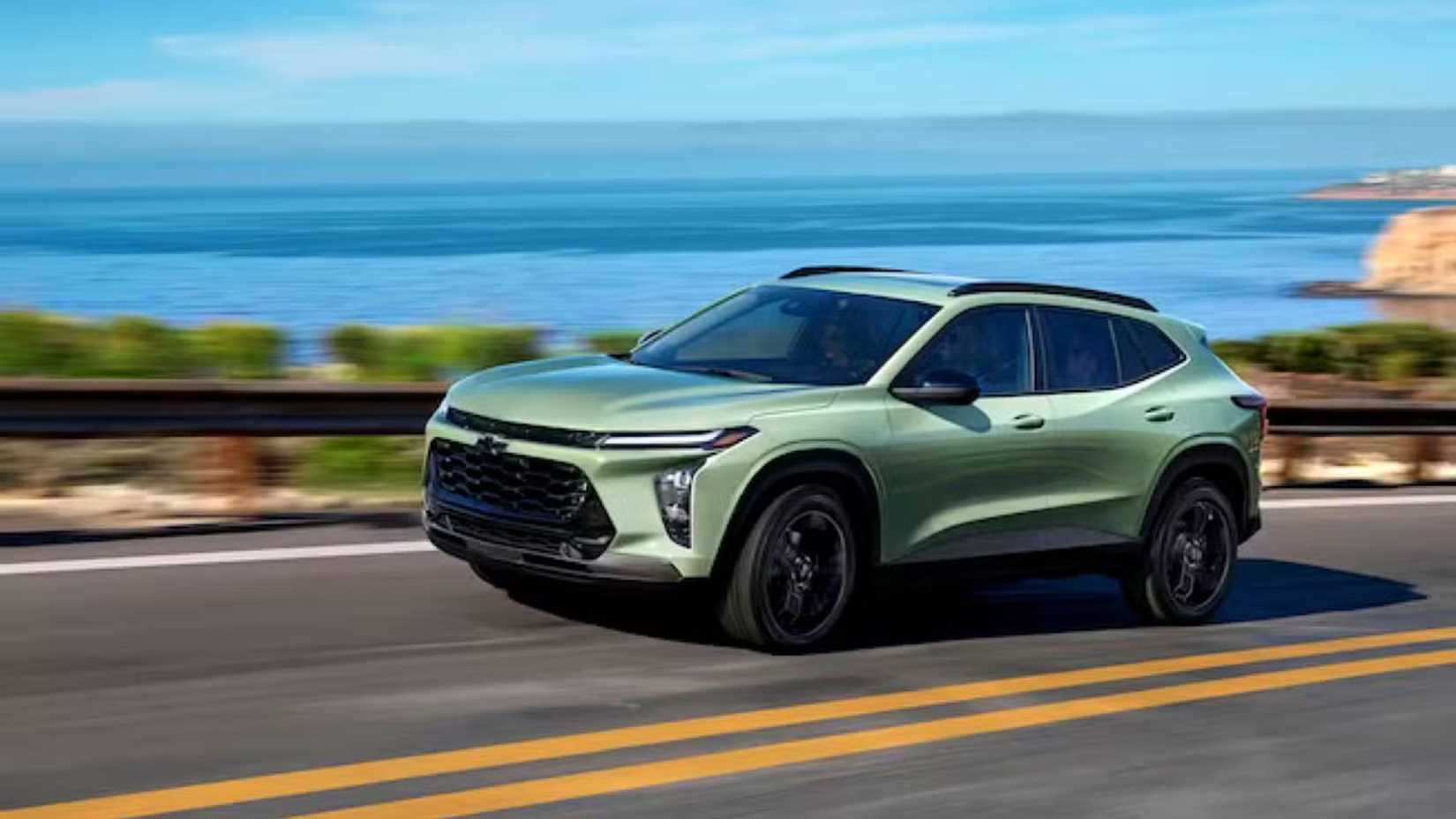 Dynamic side profile shot of 2024 Chevrolet Trax in green driving on a coastal road.