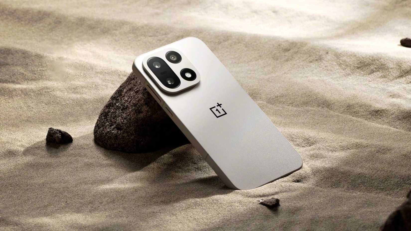 OnePlus 15 sitting in some sand.