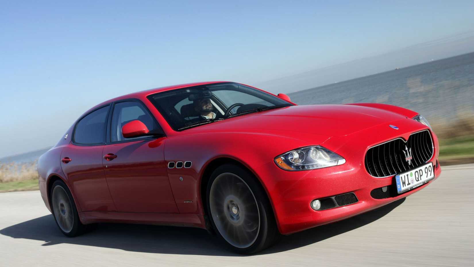Foto frontal dinâmica 3/4 de um Maserati Quattroporte 2008 vermelho.