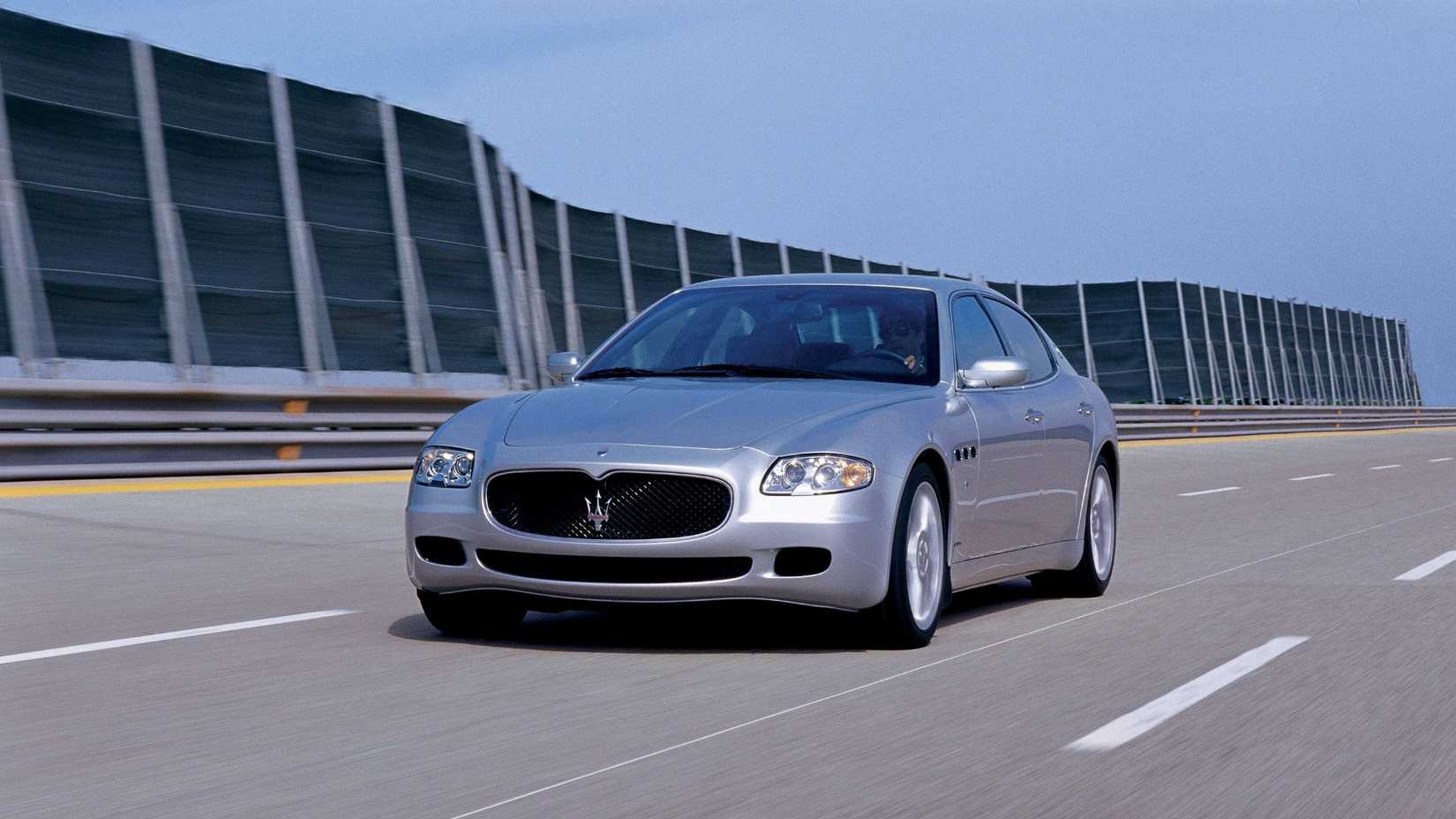 Foto frontal dinâmica 3/4 de um Maserati Quattroporte V 2003 prateado.