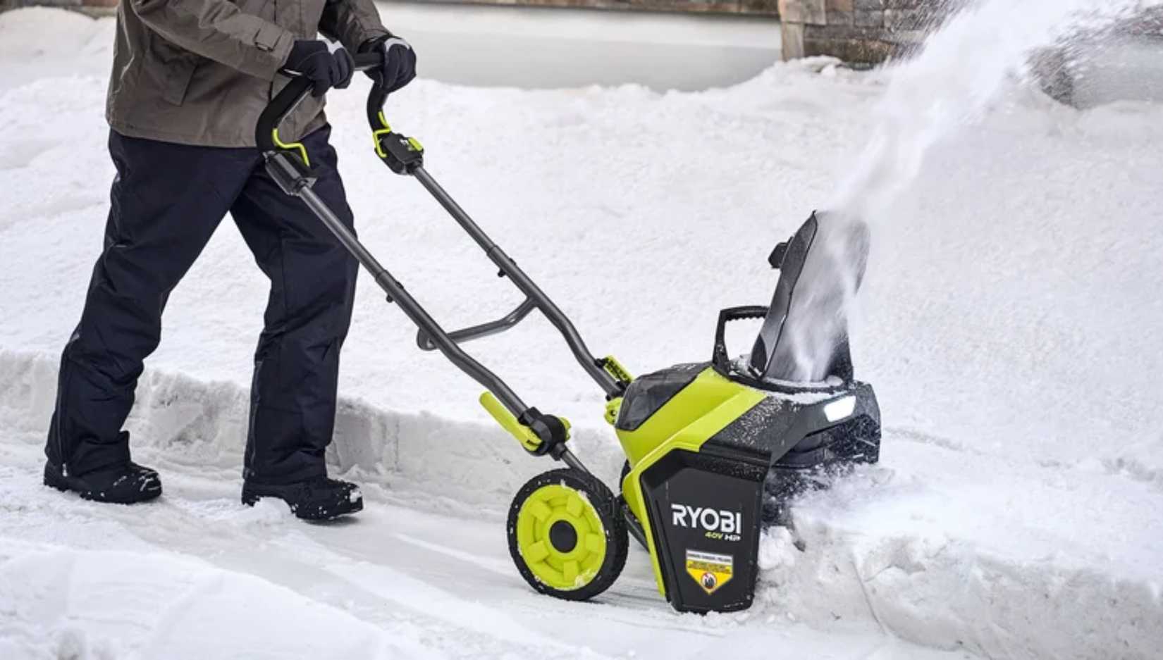 person pushing a Ryobi snowblower. 