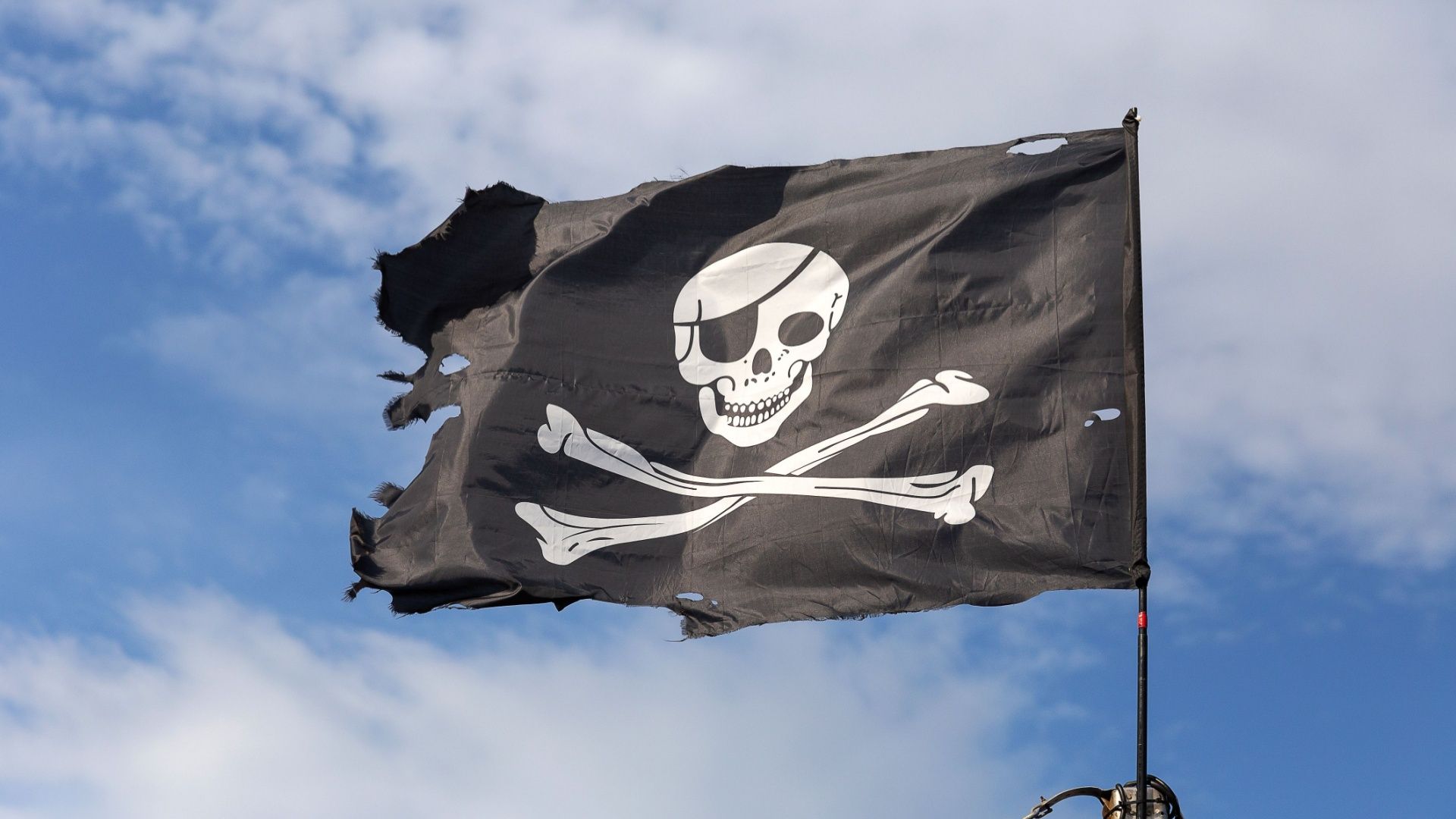 Jolly Roger pirate flag against a blue sky..