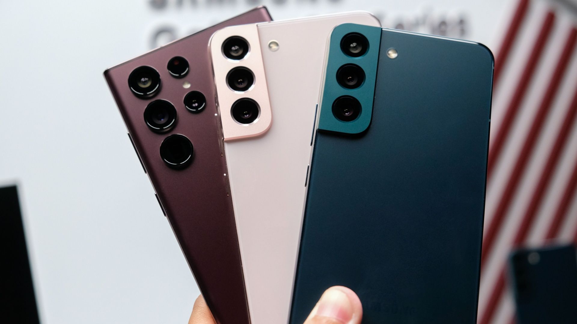 Three Galaxy flagship phones from Samsung held fanned in a person's hand.