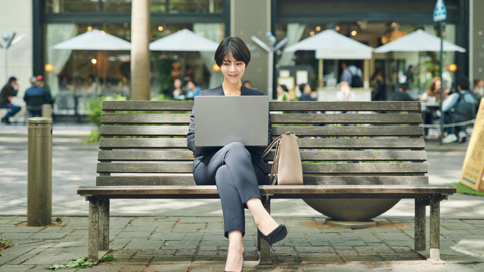 An office worker in her thirties checks her work on a bench.