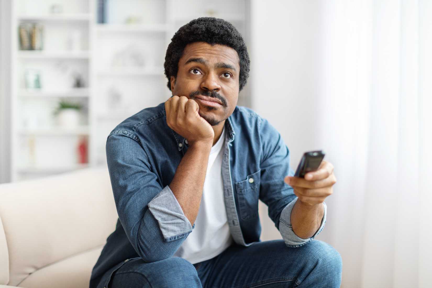 Bored young man watching TV at home.