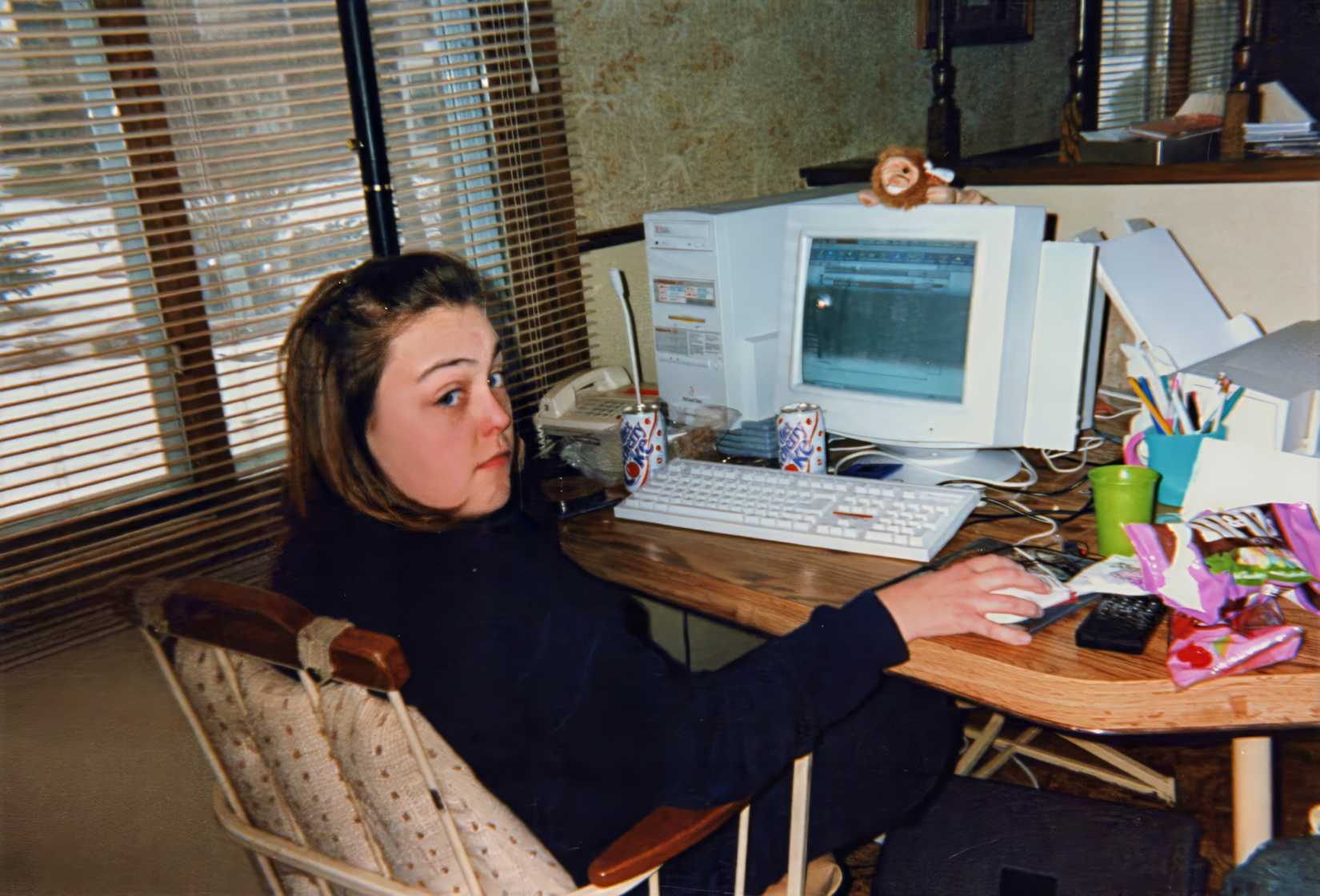 A teenage girl uses America Online (AOL), surfing the Internet on a desktop computer, with lots of snacks and sodas.